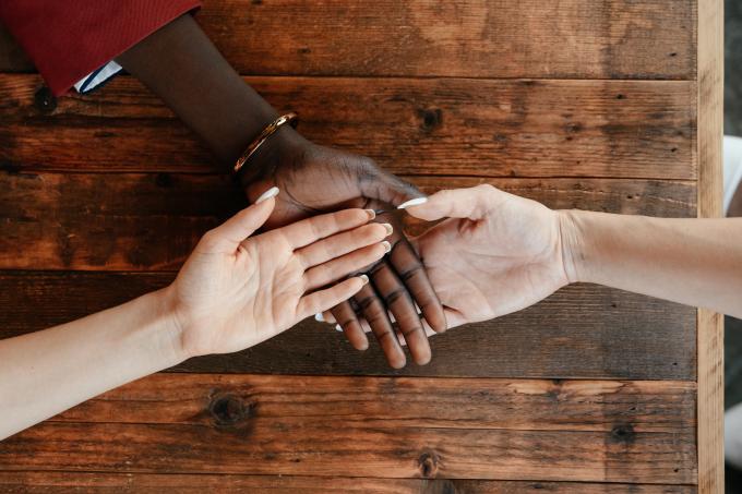 Diverse women stacking hands on wooden table